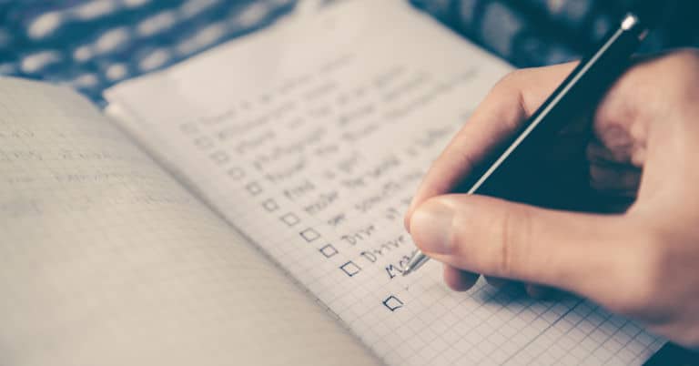 A person planning steps in a planner with a pen.