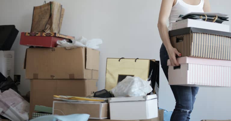 A woman decluttering by packing and moving boxes of clutter.