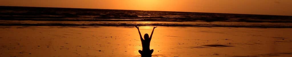 A peaceful woman on a beach at sunset.