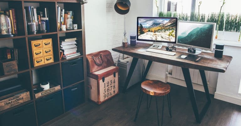 A cluttered home office with a stool for a chair at the desk.